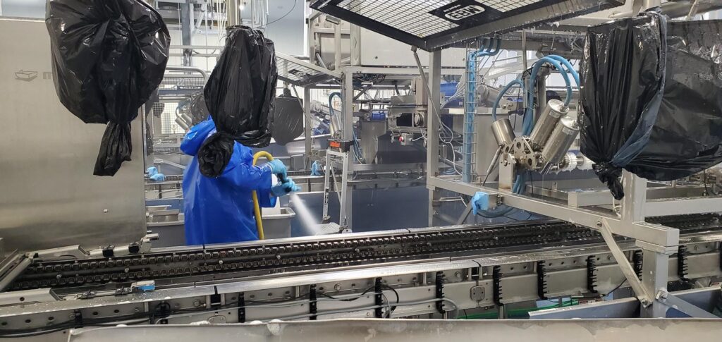 Production worker performing a washdown cleaning  in the plant production area.